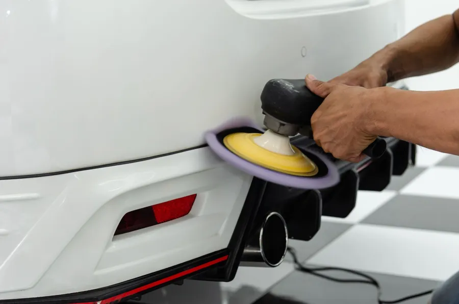 Close-up of a polisher working on a white bumper
