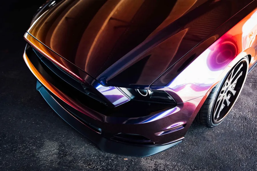 Glossy custom-painted sports car front end with strong reflections